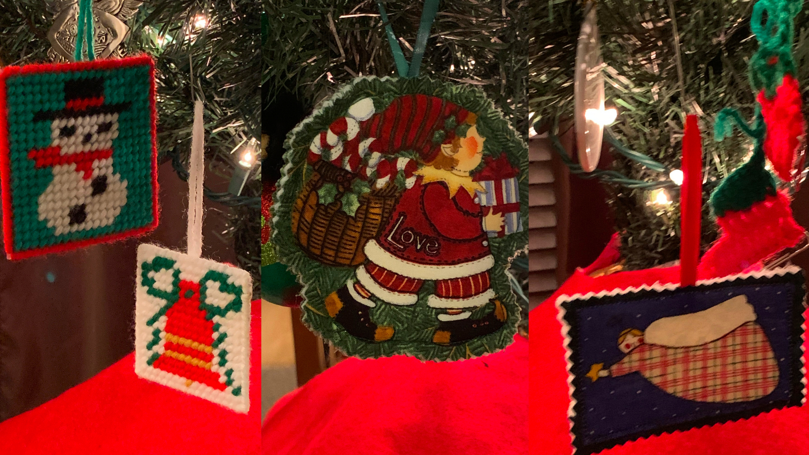Close-up of Christmas tree ornaments, including cross-stitched designs of a snowman, a red and green hat, an angel, and a round Santa decoration with the word "Love.