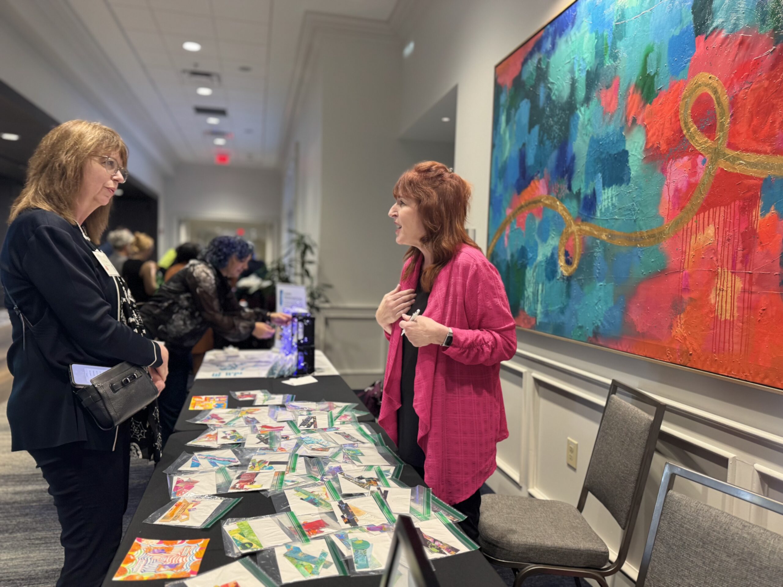 Two women looking at a table covered with colorful materials at an educational program.