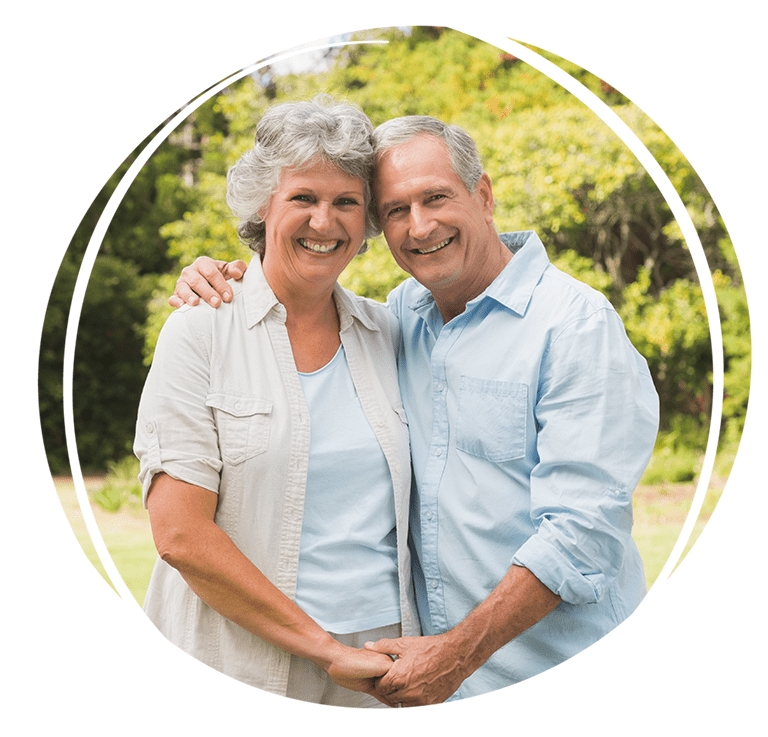 An older couple standing outdoors, smiling and holding hands while dressed casually. An older couple standing outdoors, smiling and holding hands while dressed casually.